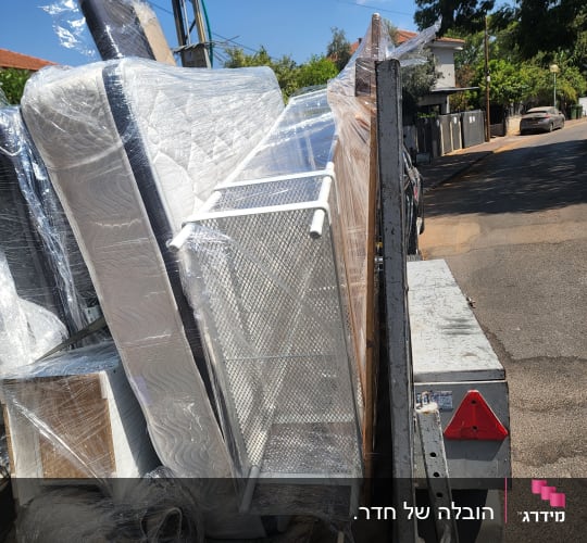 רהיטים עטופים בניילון על עגלה ברחוב